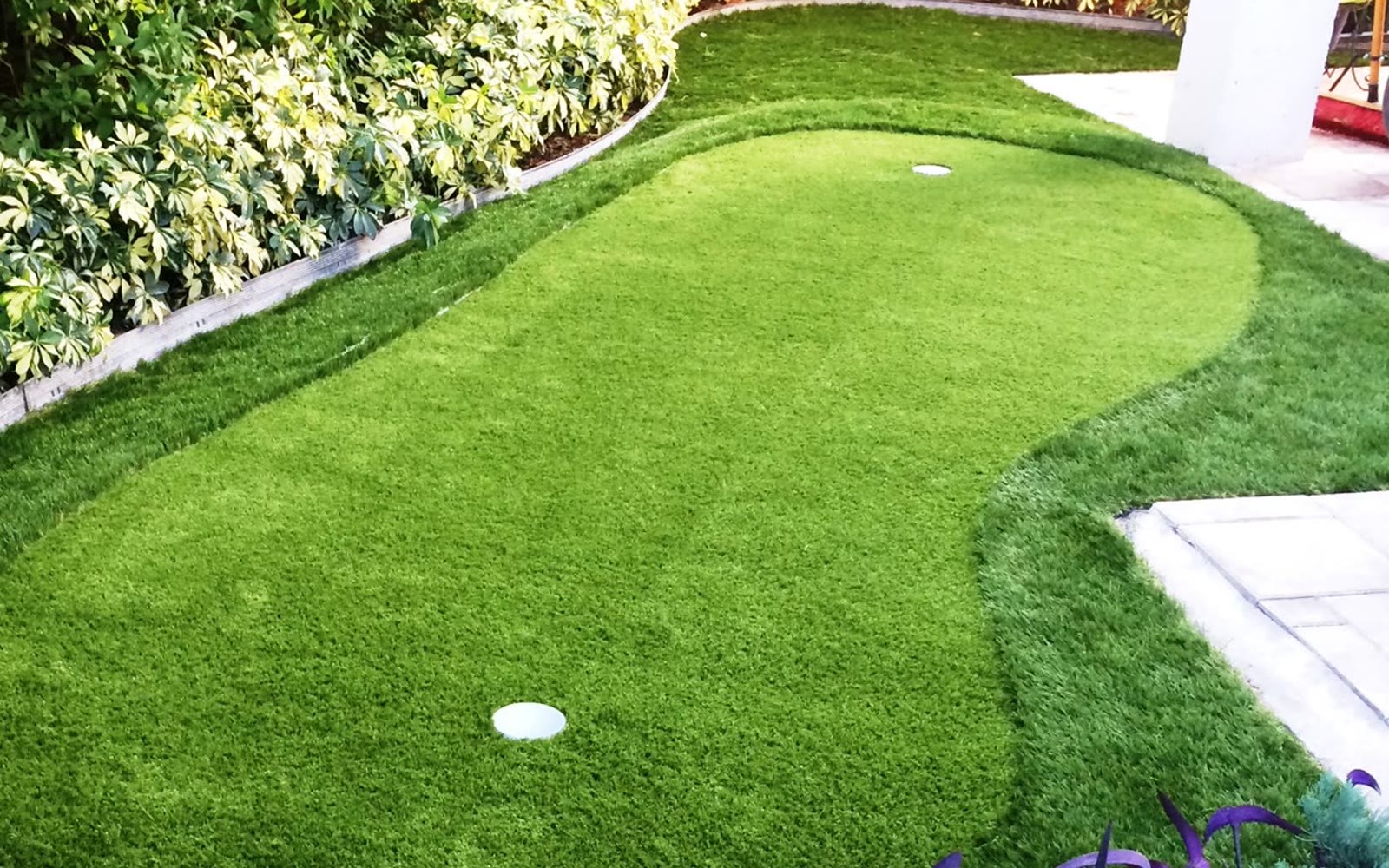 Artificial-turf putting green in a landscaped backyard